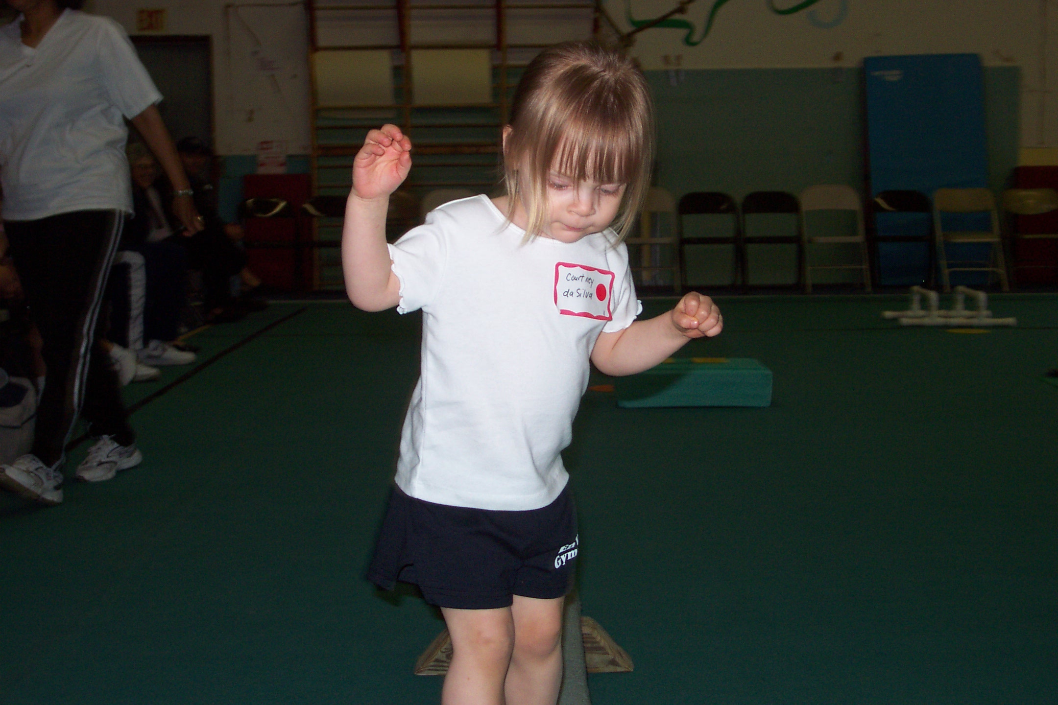 A very small Courtney keeps balance on beam.